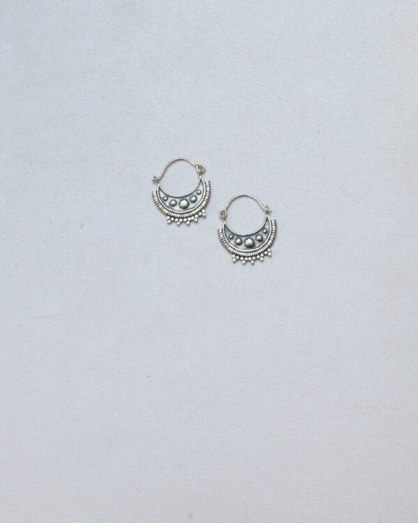 Solid silver hoops with tribal design are pla.ced on a white surface